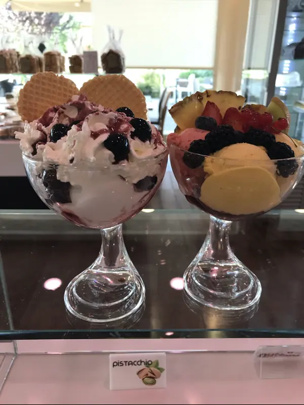 Due coppe di gelato artigianale Martinazzo con panna, frutti di bosco e cialda, servite nel dehor esterno