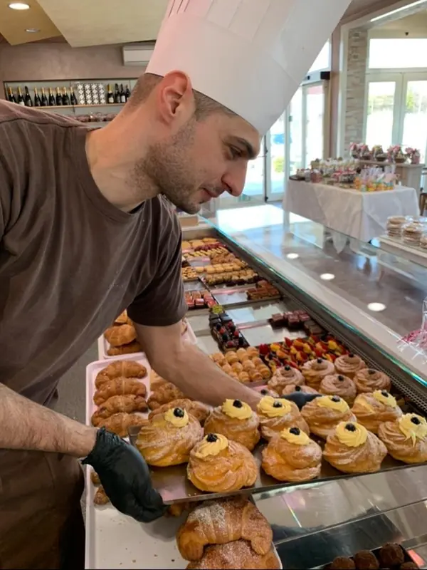 Il pasticcere al lavoro sul vassoio di mignon appena farciti, nel laboratorio Martinazzo di Rodigo