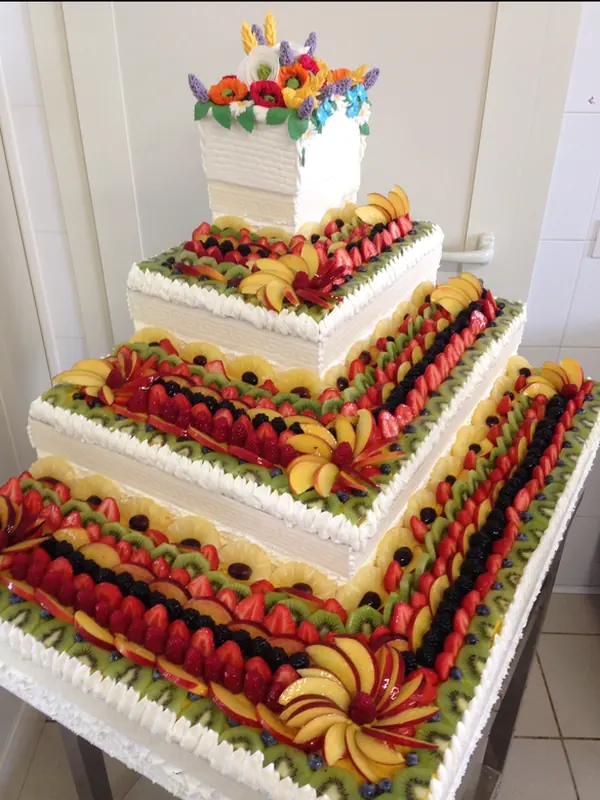 Torta nuziale a piani quadrati decorata con frutta fresca, realizzata su misura dalla Pasticceria Martinazzo
